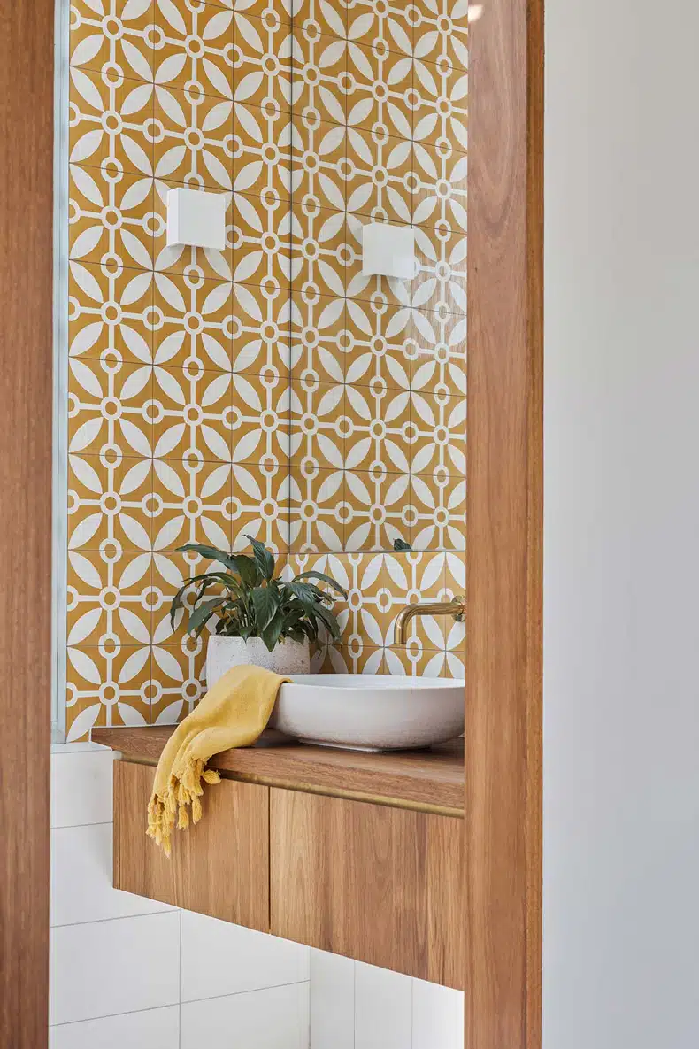 A bathroom with a yellow and white tiled wall.