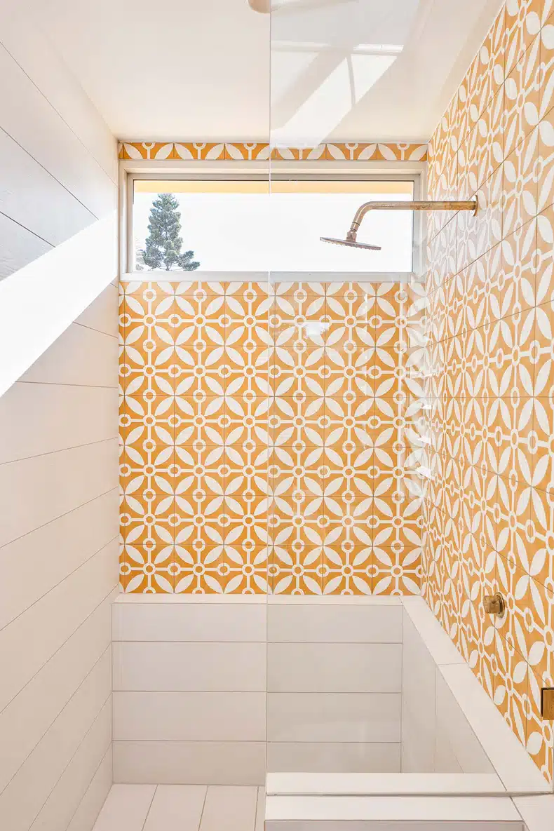 A yellow and white tiled shower with a window.
