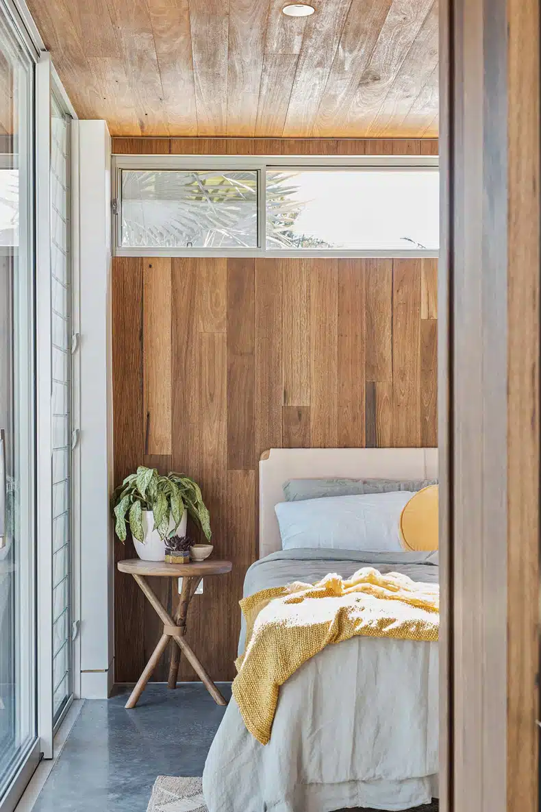 A bedroom with wooden walls and a sliding glass door.