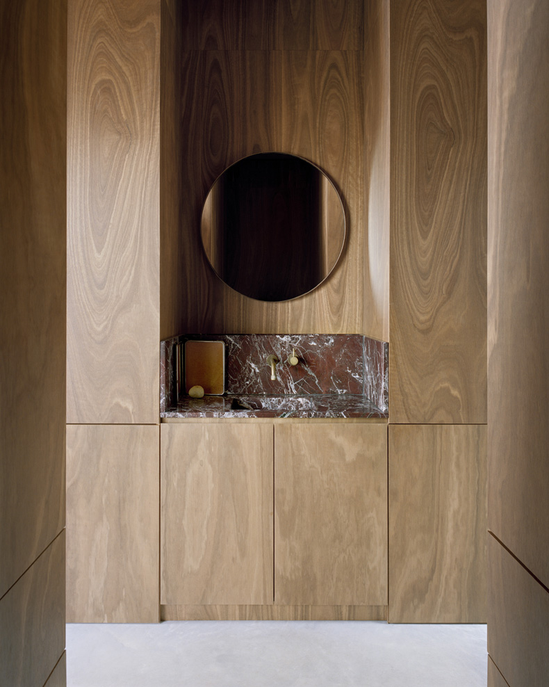 Mary Street House By Edition Office features a bathroom with wooden walls and a round mirror.