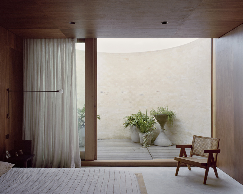 A bedroom with a bed, a chair, and a window designed by Edition Office.