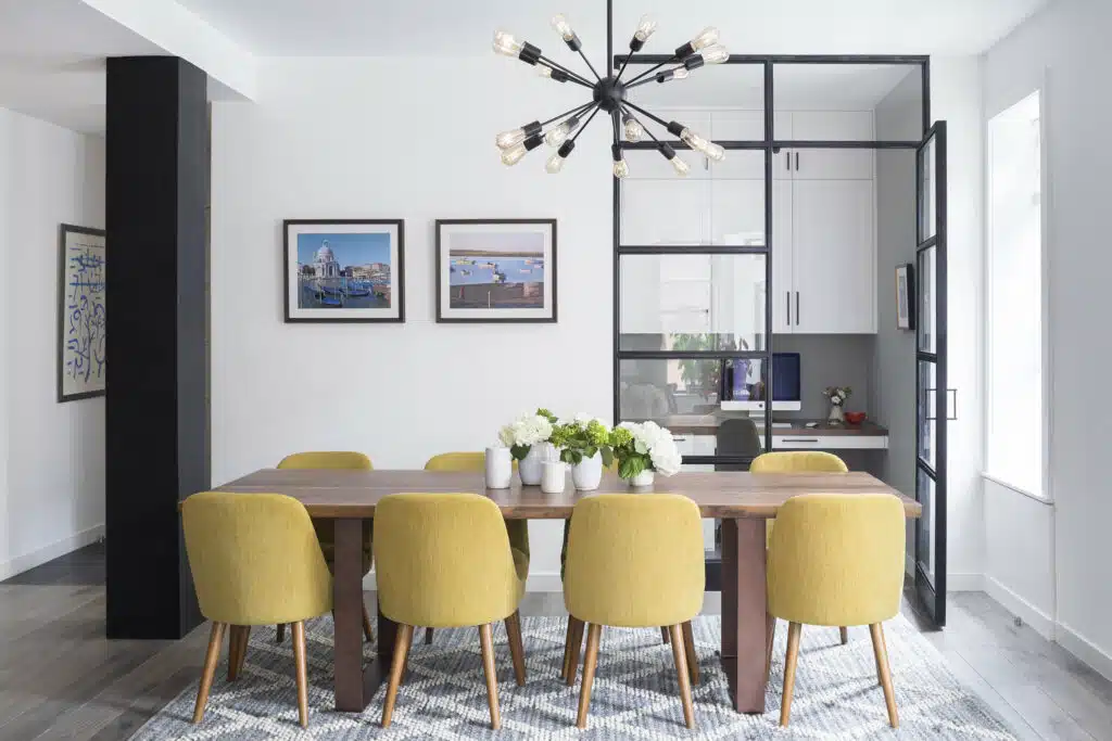 A dining room with yellow chairs and a black table.