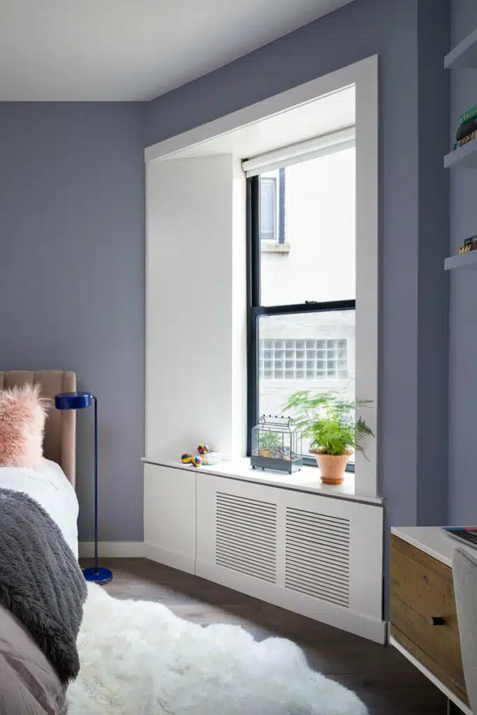 A bedroom with blue walls and a window.