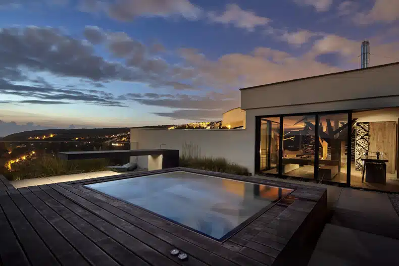 A house with a jacuzzi on the roof at dusk.
