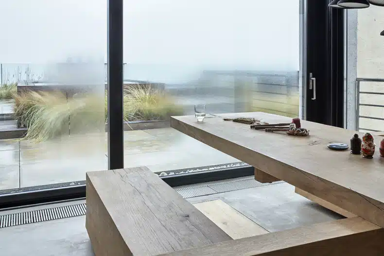 A wooden table with a bench in front of a window.
