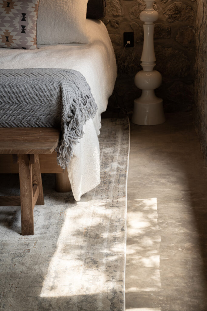 Petraia House: A bed in a stone-walled room.