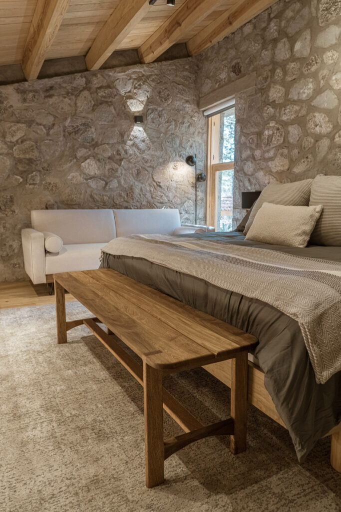 A bed in a Petraia House bedroom with stone walls.