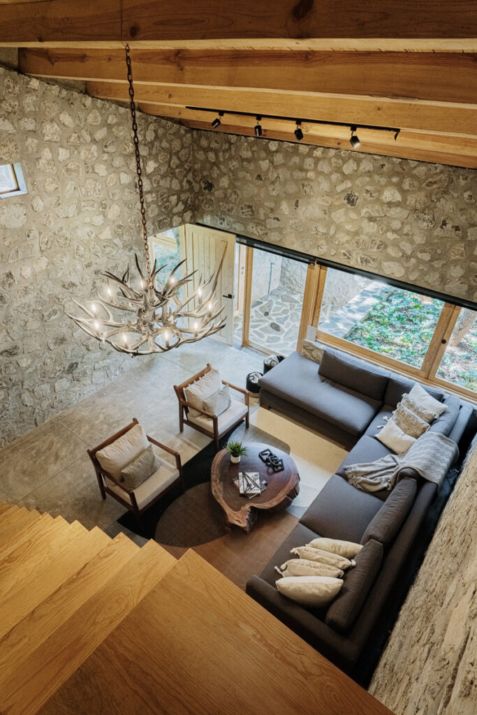 Petraia House showcases a living room with striking stone walls and warm wooden floors.