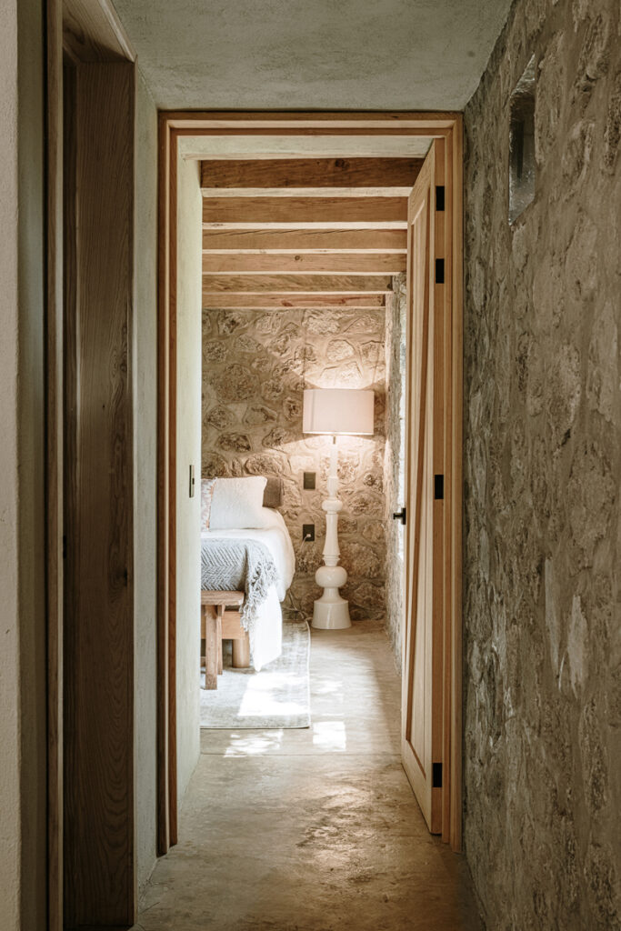 Petraia House, featuring stone walls, offers a hallway leading to a bedroom.