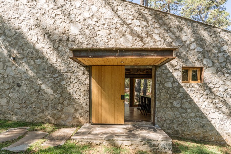 Argdl's Petraia House, nestled within the woods, exudes rustic charm with its stone walls and wooden door.