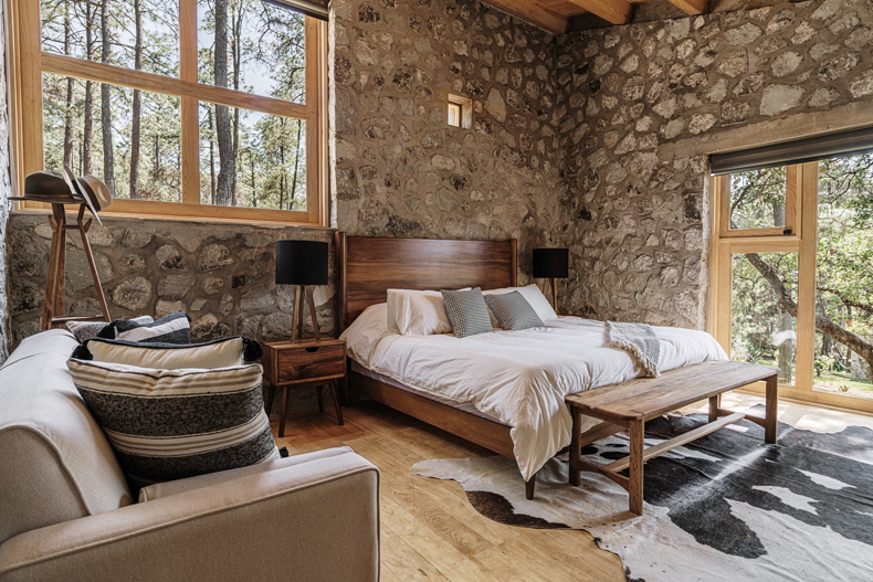 A bedroom with Petraia House's stone walls and a comfortable bed.