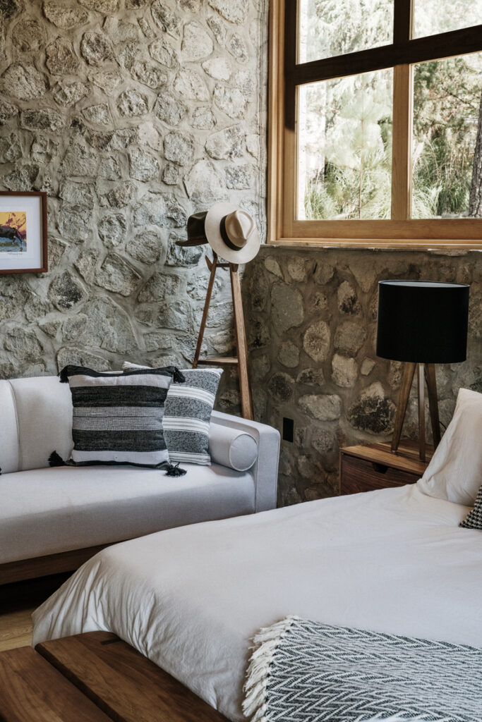 A bed in Petraia House with a stone wall.