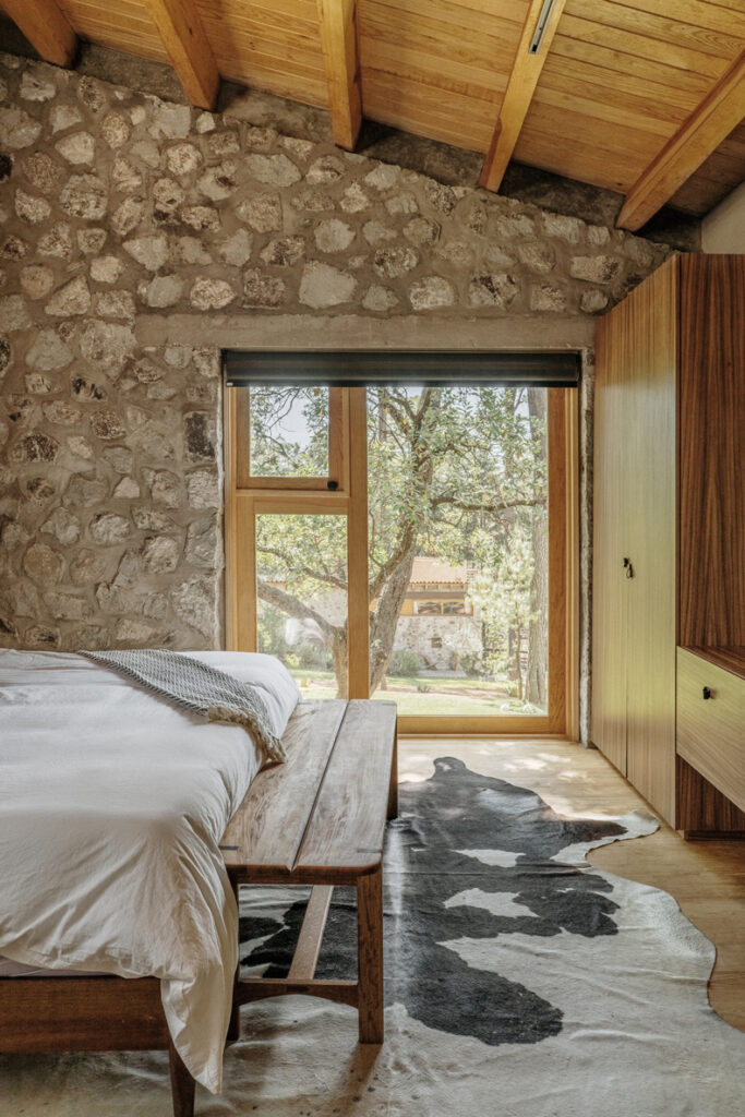 A bedroom in Petraia House with stone walls and a cowhide rug.