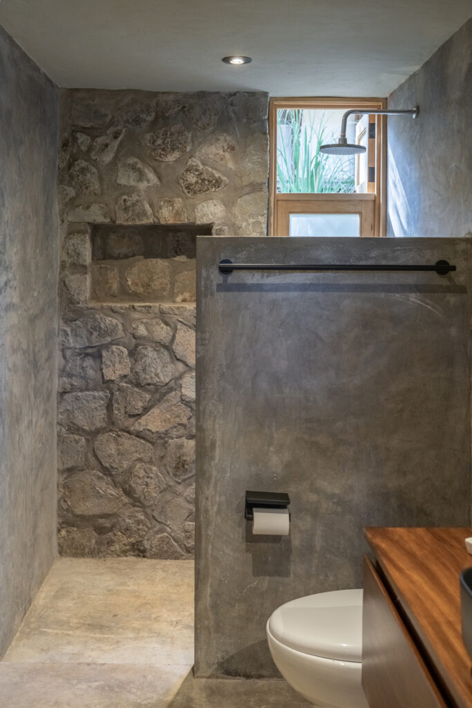Petraia House By Argdl showcases a lavatory featuring stone walls and a toilet.