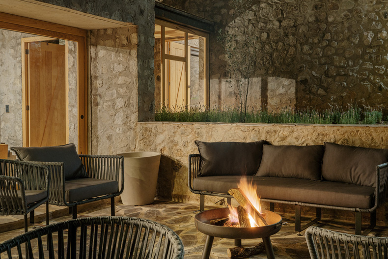 A Petraia House with a fire pit in front of a stone wall.