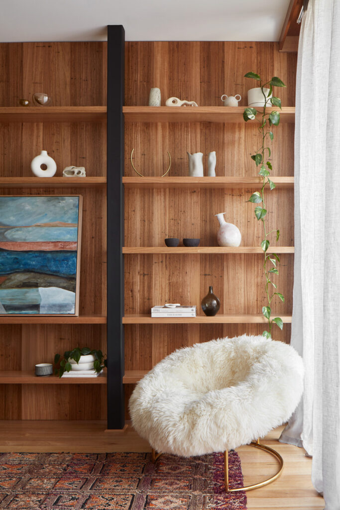 Through The Looking Glass By Ben Callery Architects: A living room with wooden shelves and a furry chair.