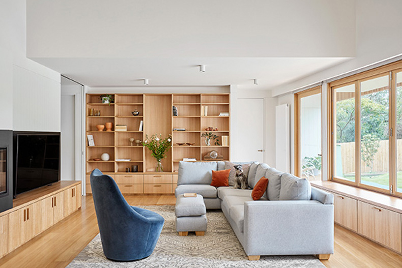 A living room with wooden shelves and a couch in the Twin Peaks House by Mihaly Slocombe.