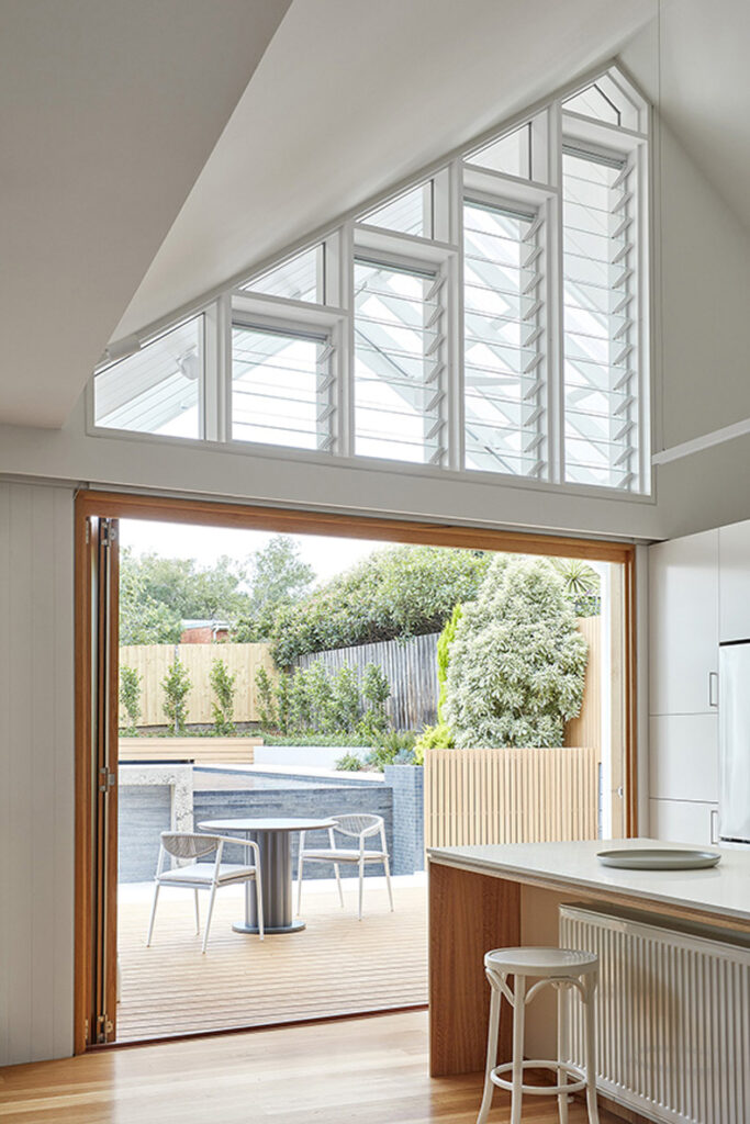 Twin Peaks House By Mihaly Slocombe featuring a kitchen with a large window overlooking a patio.