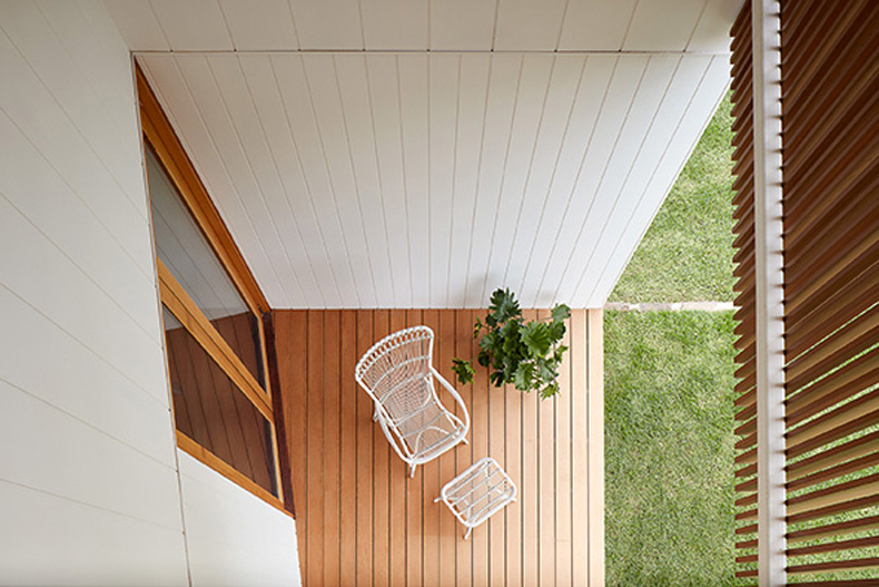 A white chair sits on a wooden deck at Twin Peaks House By Mihaly Slocombe.