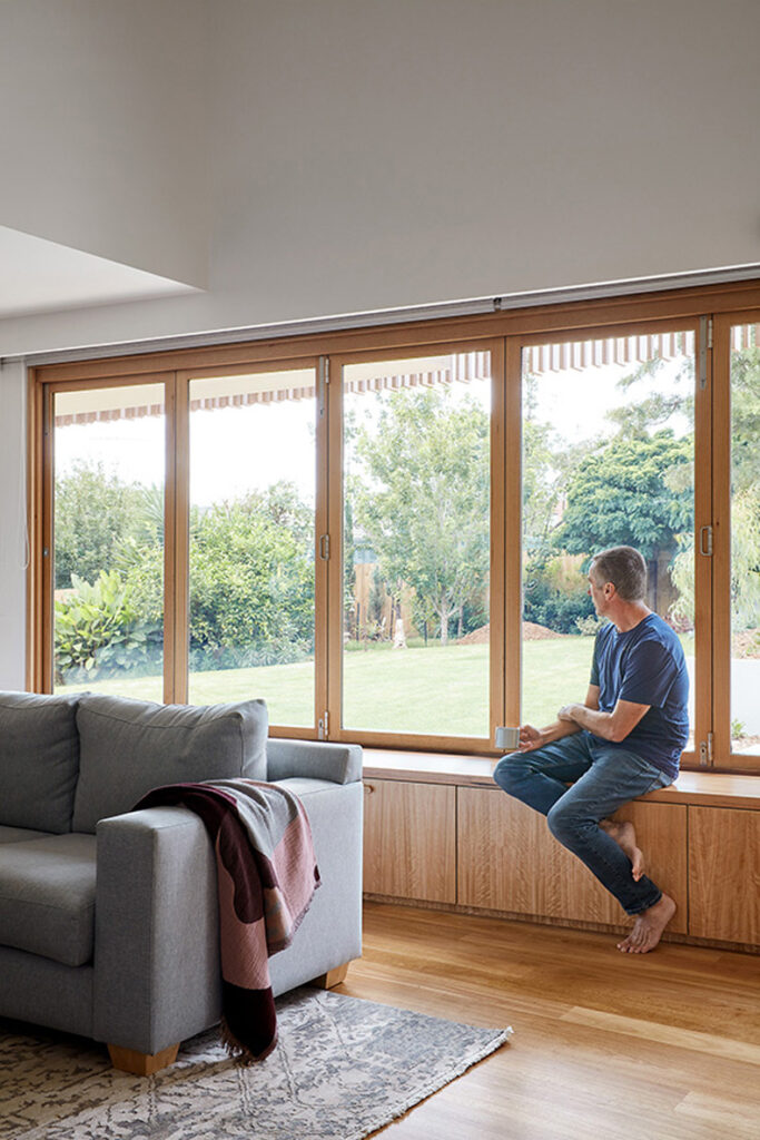 A man sitting on a Twin Peaks House couch looking out of a window.