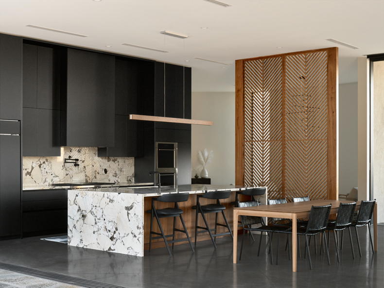 A modern kitchen with black cabinets and marble counter tops.