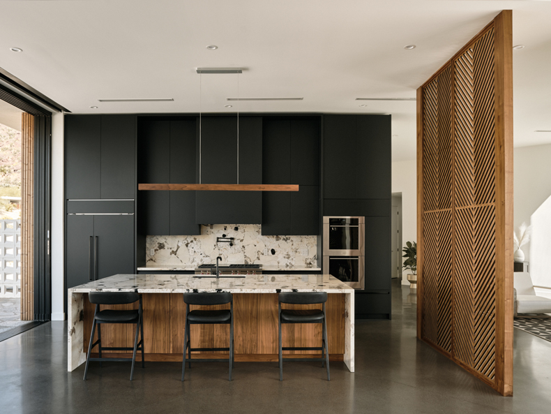 A modern kitchen with black cabinets and wooden floors.