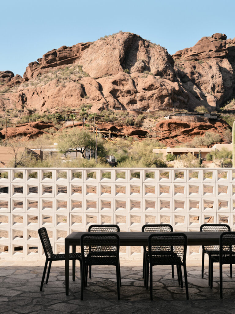 A dining table with chairs in front of a rock wall.