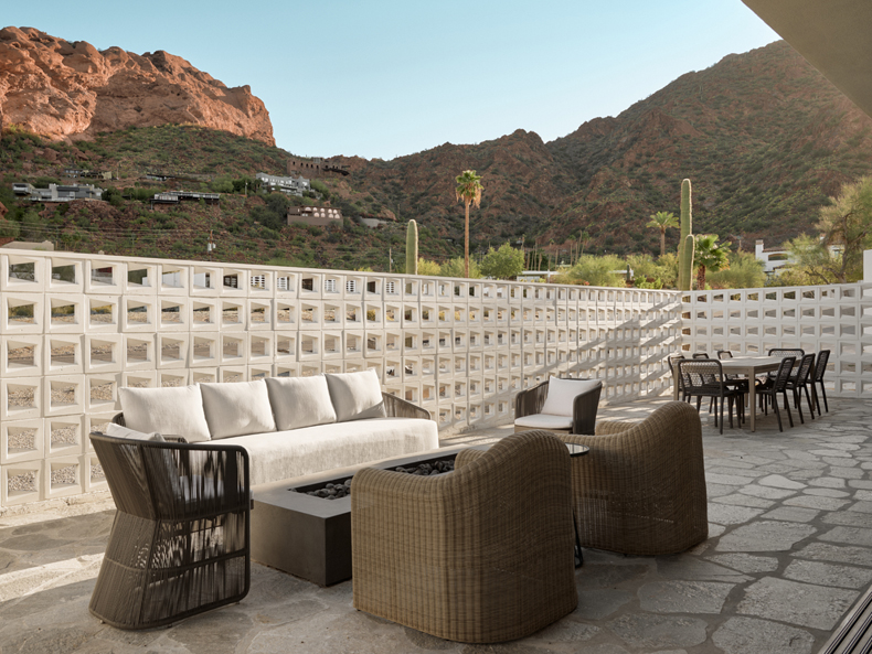 A patio with wicker furniture and mountains in the background.