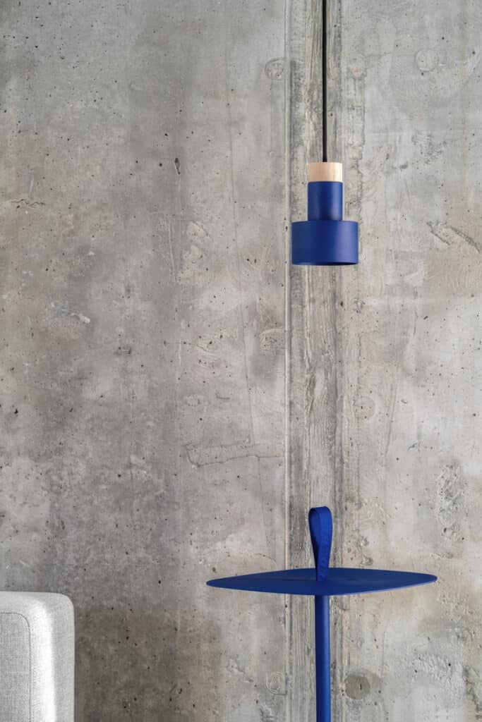 A blue table with a lamp hanging over it in the Zaricnyy Apartment by Kouple.