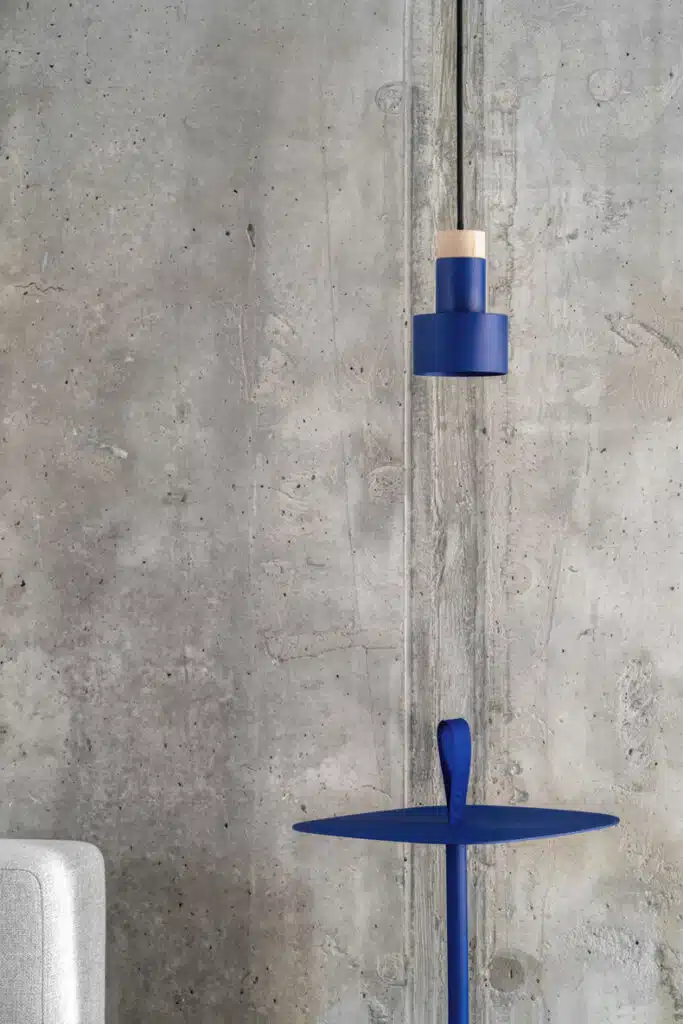A blue table with a lamp hanging over it in the Zaricnyy Apartment by Kouple.