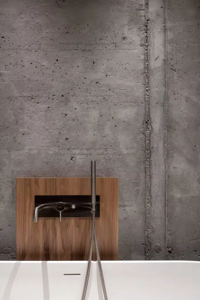 Zaricnyy Apartment: A bathroom featuring a concrete wall and a wooden sink.