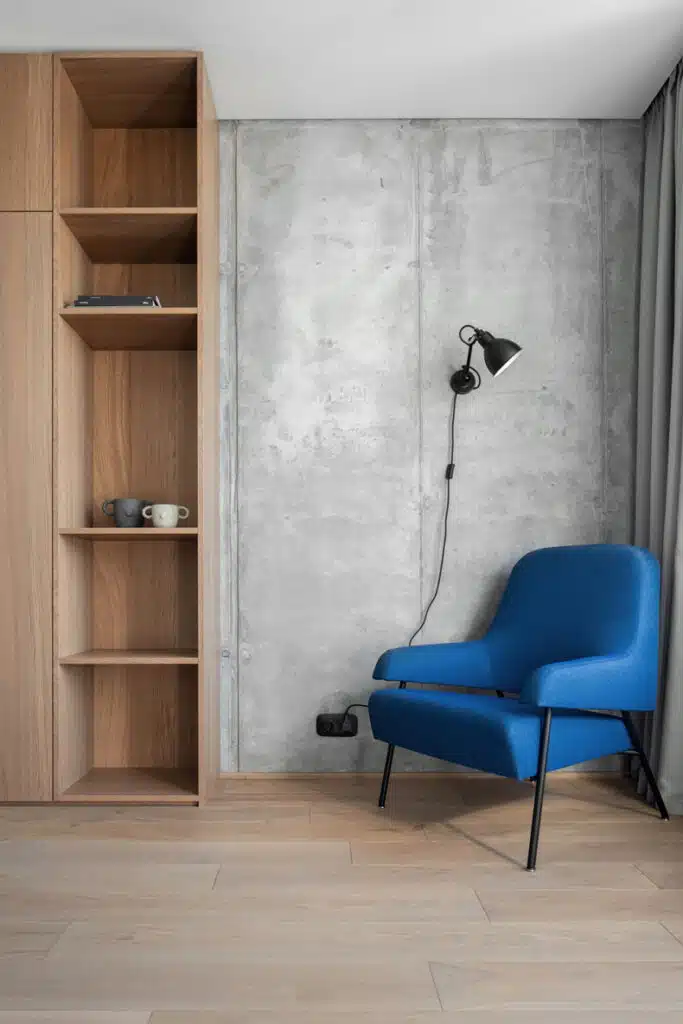 Zaricnyy Apartment by Kouple featuring a room with a blue chair and a bookcase.