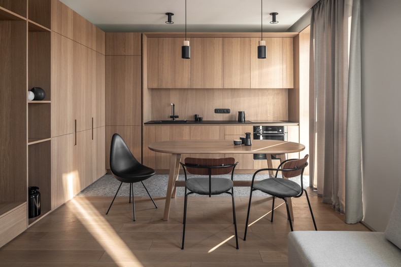 Zaricnyy Apartment By Kouple with wooden cabinets and a dining table.