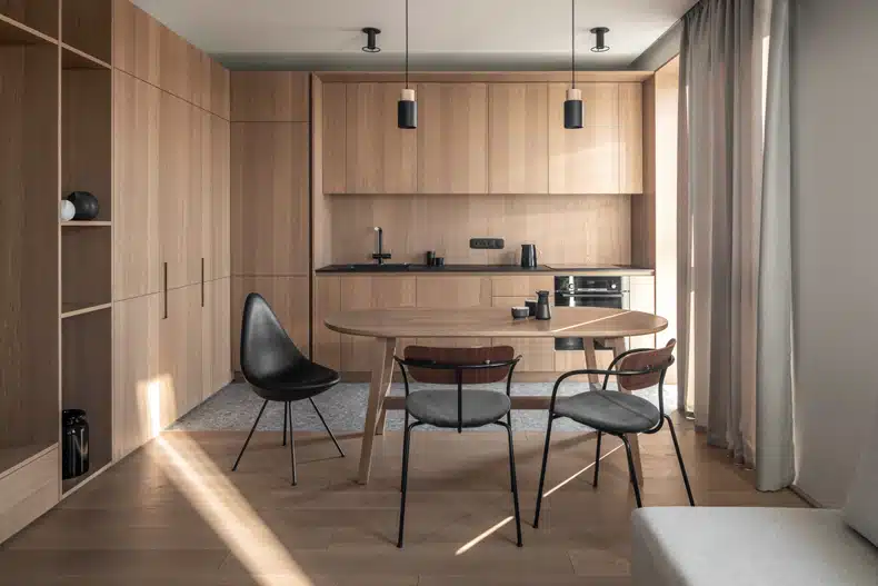 Zaricnyy Apartment By Kouple with wooden cabinets and a dining table.