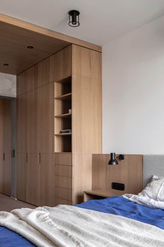 A bedroom with wooden cabinets and a blue comforter in the Zaricnyy Apartment.