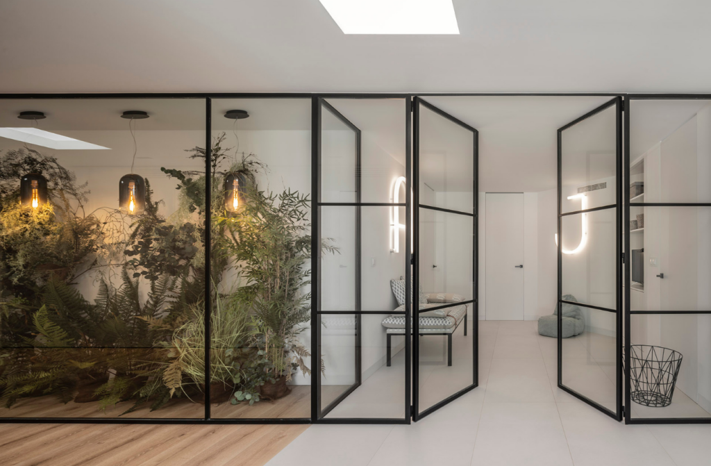Citric House, designed by Susanna Cots Interior Design, features a room adorned with glass doors and vibrant plants.