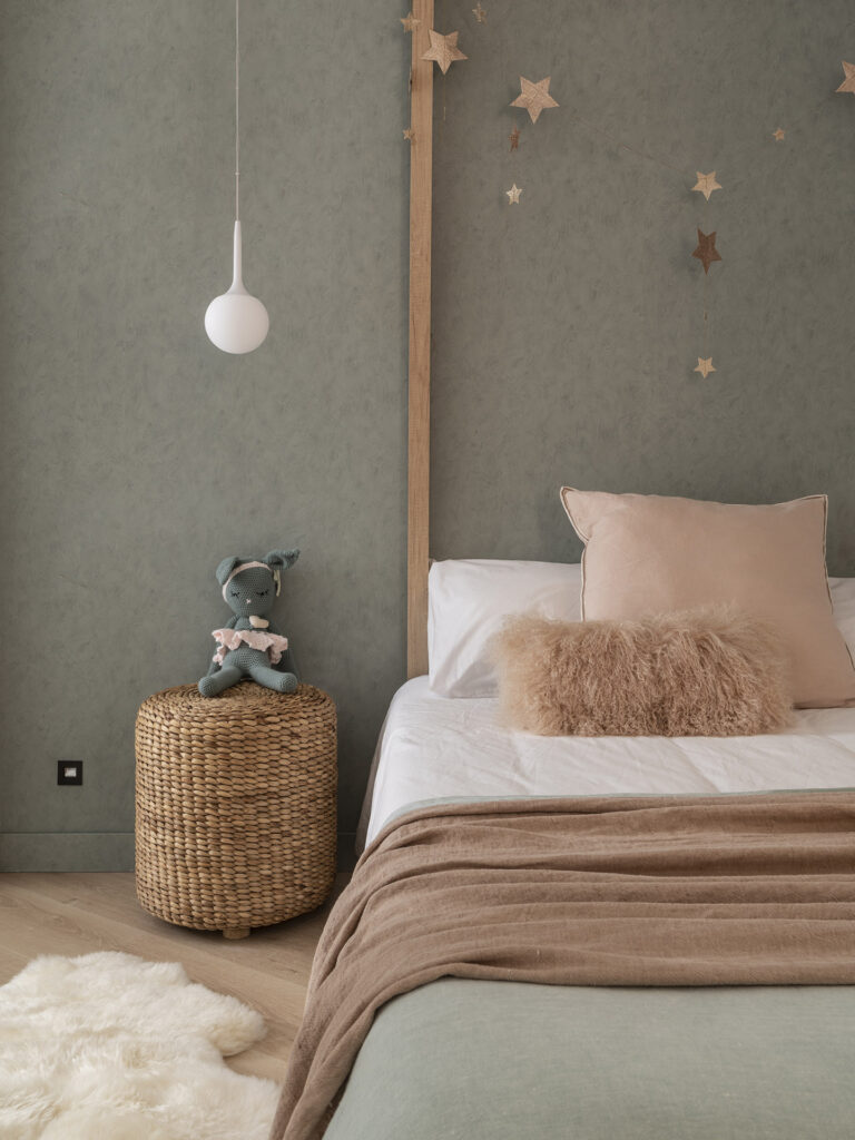 A child's bedroom with a green wall and stars on the wall designed by Susanna Cots Interior Design.