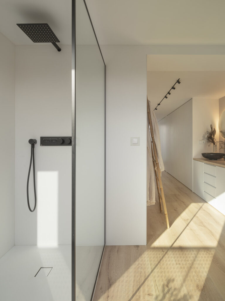 Citric House by Susanna Cots Interior Design features a glass shower and wooden floor in the bathroom.