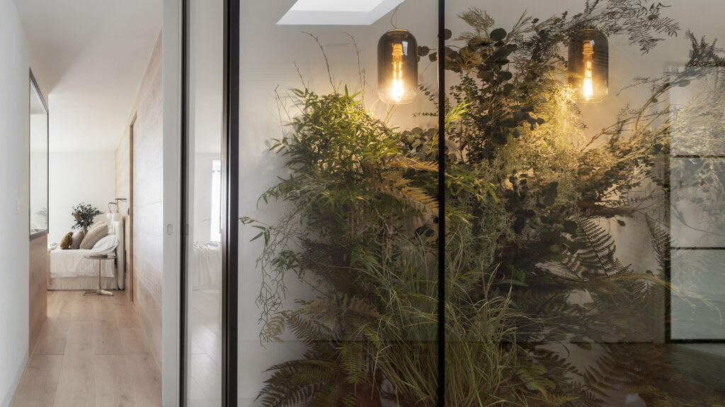 A Citric House hallway with plants and a glass door designed by Susanna Cots Interior Design.