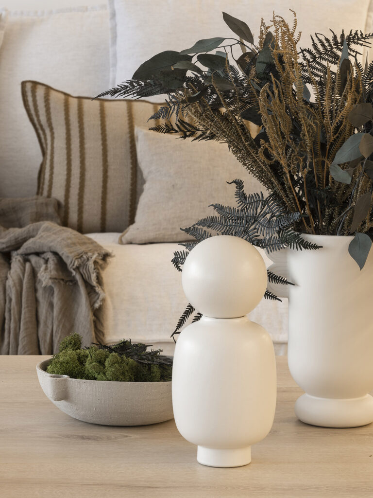 Two white vases on a table next to a couch in the Citric House by Susanna Cots Interior Design.