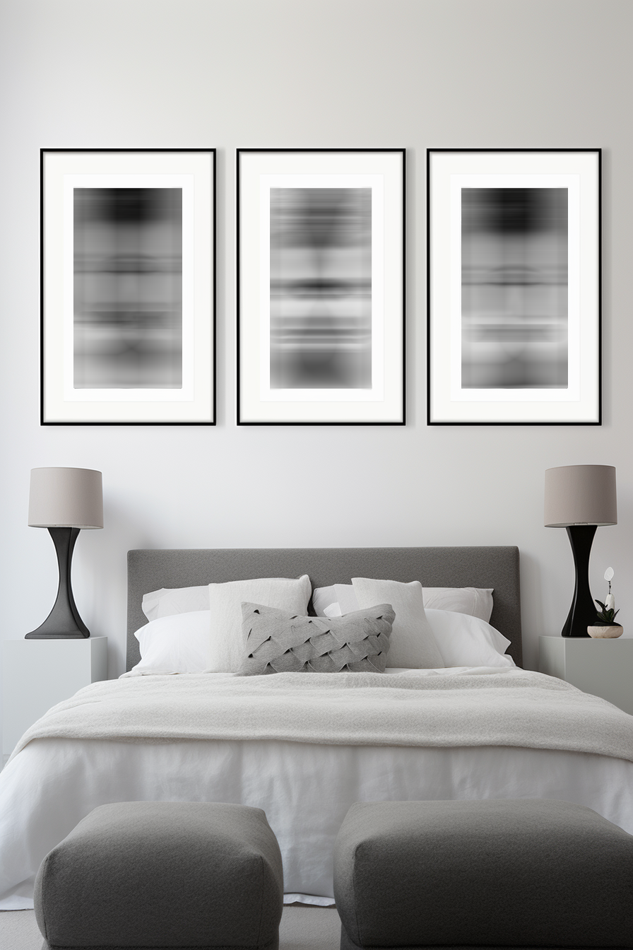 Three black and white framed prints providing room decor above a bed in a bedroom.