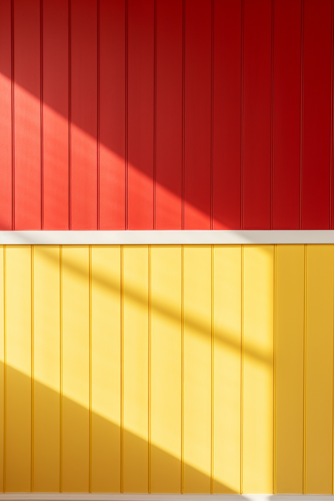 A triadic color scheme featuring a yellow, red, and blue wall harmonizing under a shining light.